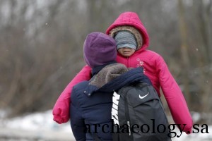 A migrant carries a child as they walk through a frozen field after crossing the border from Macedonia, near the village of Miratovac, Serbia, January 18, 2016. REUTERS/Marko Djurica