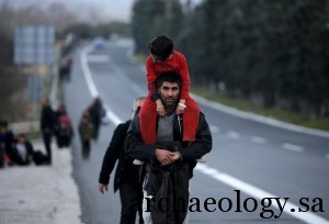 A stranded refugee carries his child along a national motorway towards the Greek-Macedonian border, February 25, 2016. REUTERS/Yannis Behrakis