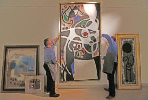 FILE - In this Thursday, Dec. 19, 2013 file photo, auction house workers adjust Joan Miro's 1968 oil painting "Women and Birds" which has an estimated sale price of 4-to-7 million pounds ($6.5 million to $11.5 million),  in a room with other works by Miro,  at Christie's auction house in central London. Portugal is hoping a master of surrealism can help taxpayers recoup some of the millions they lost rescuing a failed bank. The government is selling 85 works by Spanish artist Joan Miro that became public property when Banco Portugues de Negocios was nationalized in 2008. Christie's in London, which is handling the two-day sale starting Tuesday, Feb. 4, 2014,  describes the collection as "one of the most extensive and impressive offerings of works by the artist ever to come to auction." (AP Photo/Lefteris Pitarakis, File)